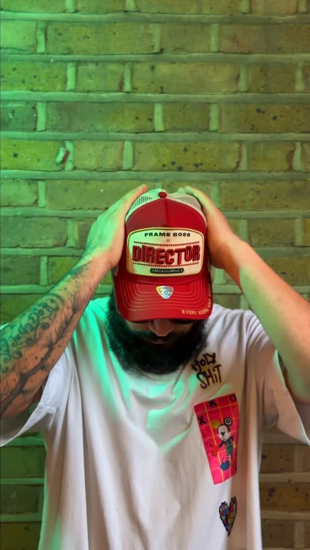 A man wearing a red and white trucker cap with director text on it.