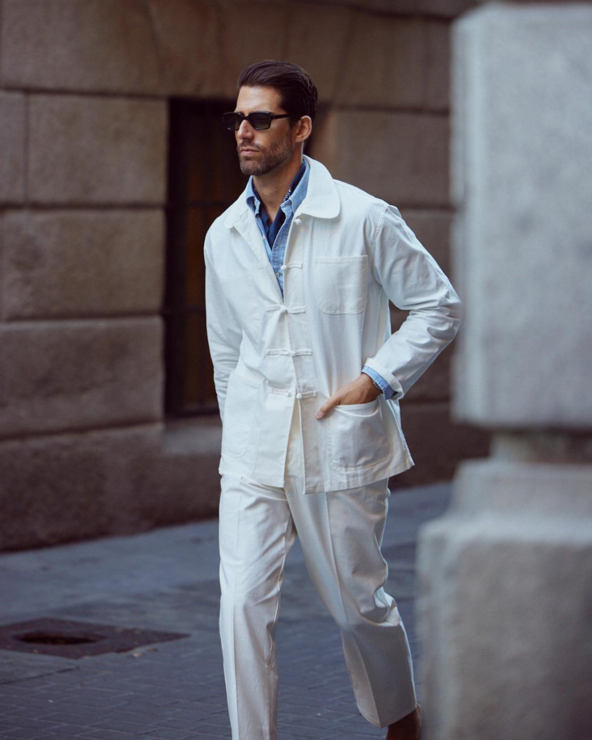 Man in a white linen suit with decorative frog-closure fastenings on his jacket.