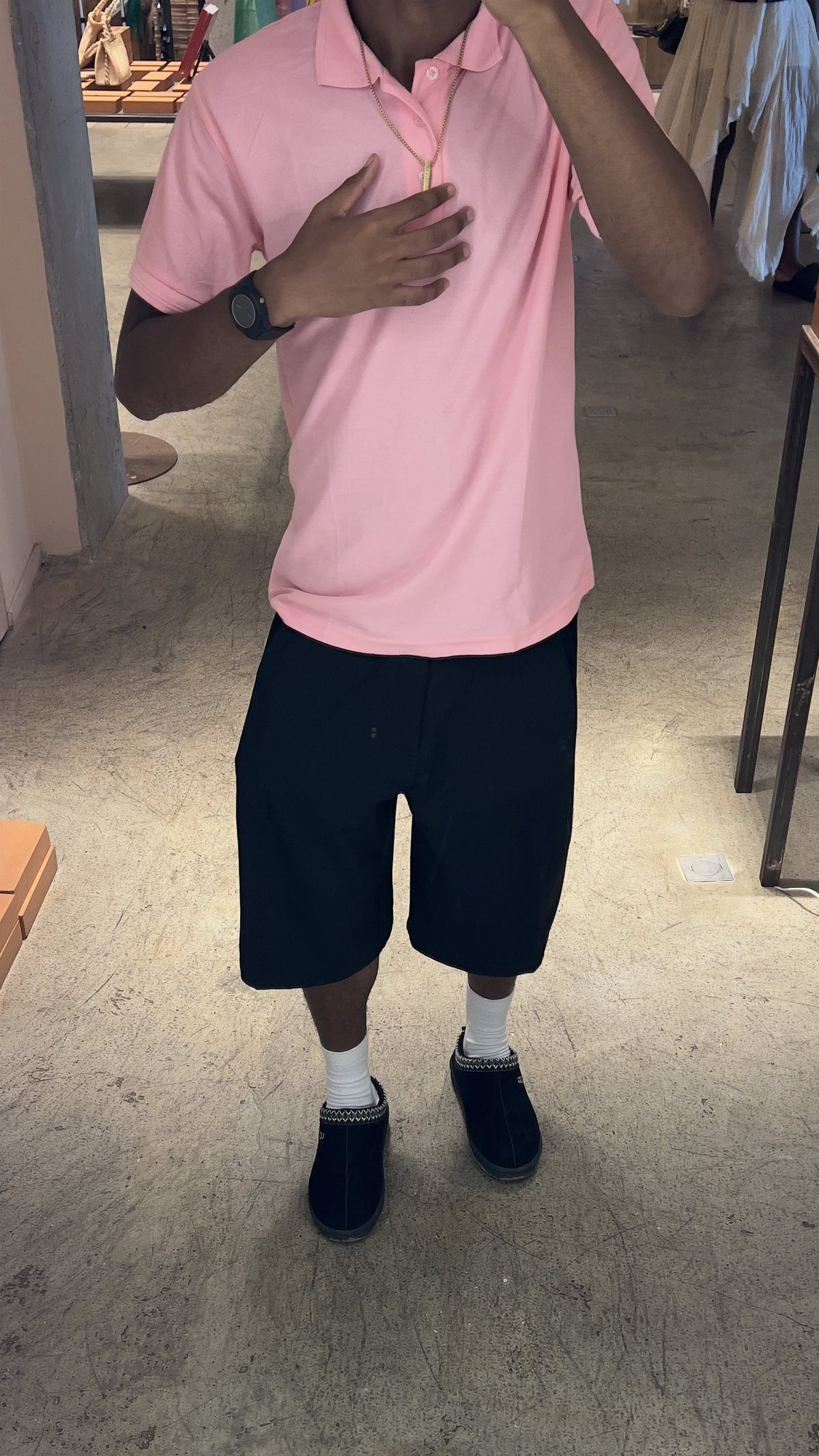 A person wearing a pink polo shirt with black shorts and black loafers.