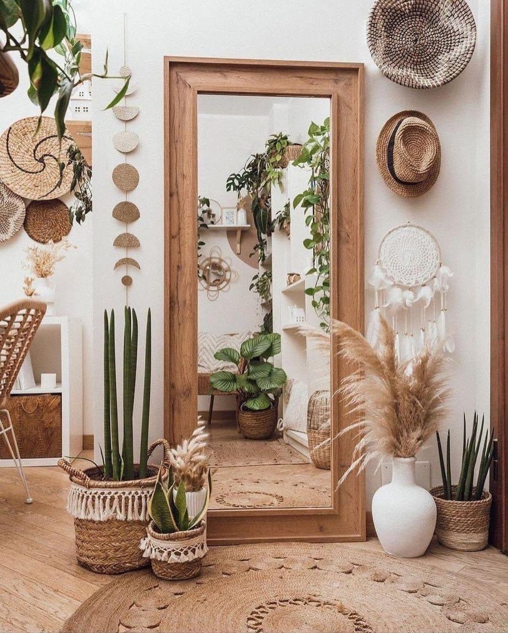 Bohemian room decor featuring a large wooden mirror, potted plants, and woven wall hangings.
