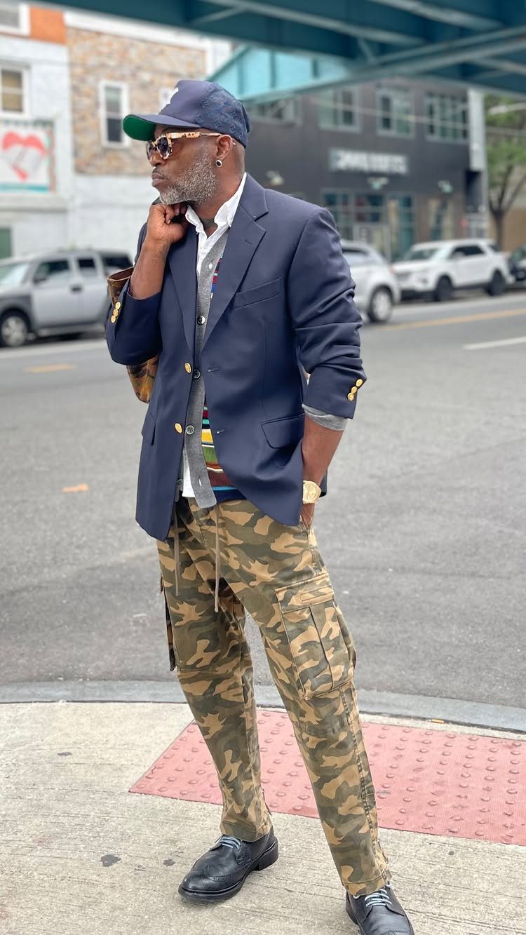 Man posing on a city street wearing a navy blazer and camouflage cargo pants.