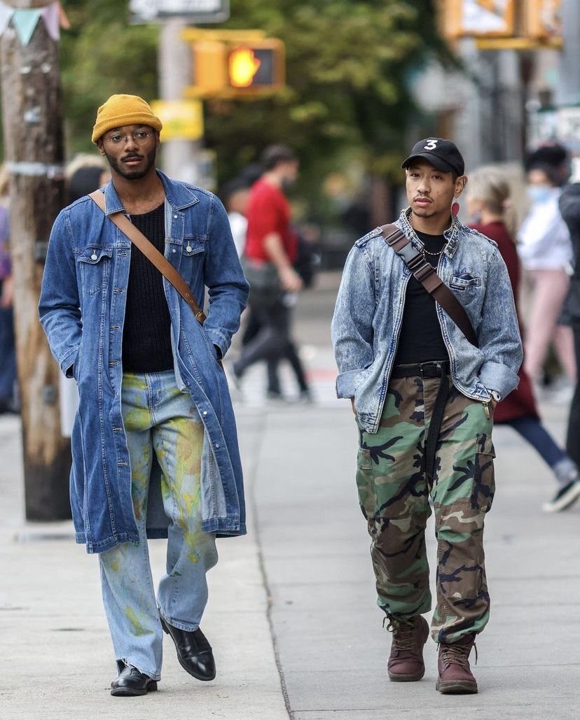 Two men walking down a city street wearing denim jackets and camouflage pants.