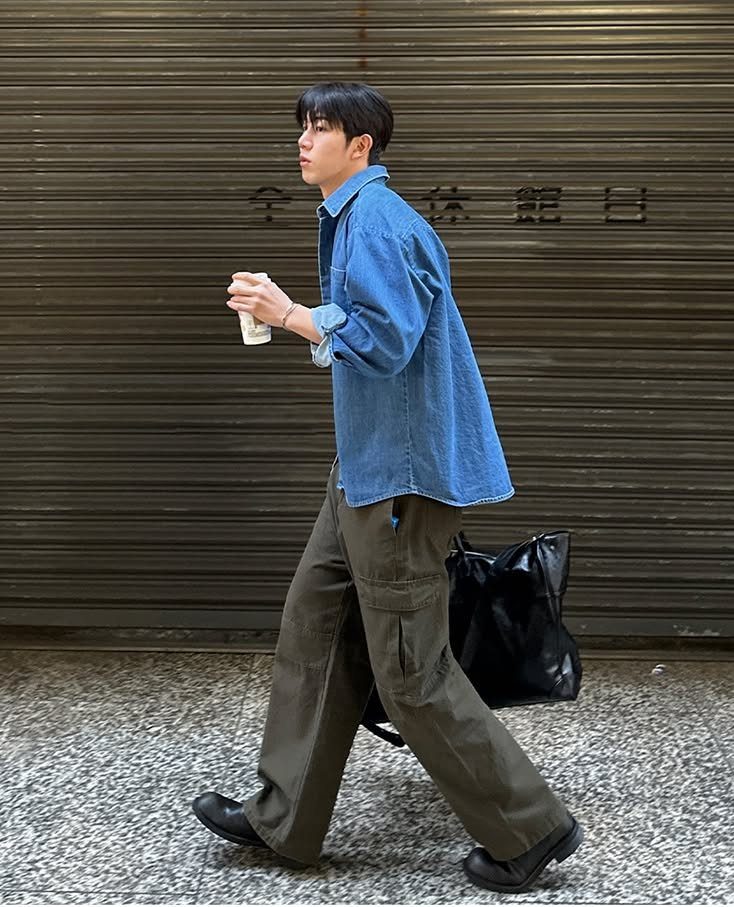 Man walking in an oversized blue denim shirt and olive green cargo pants.