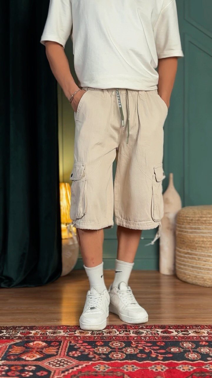 A person wearing a white t-shirt and beige cargo shorts with white sneakers.