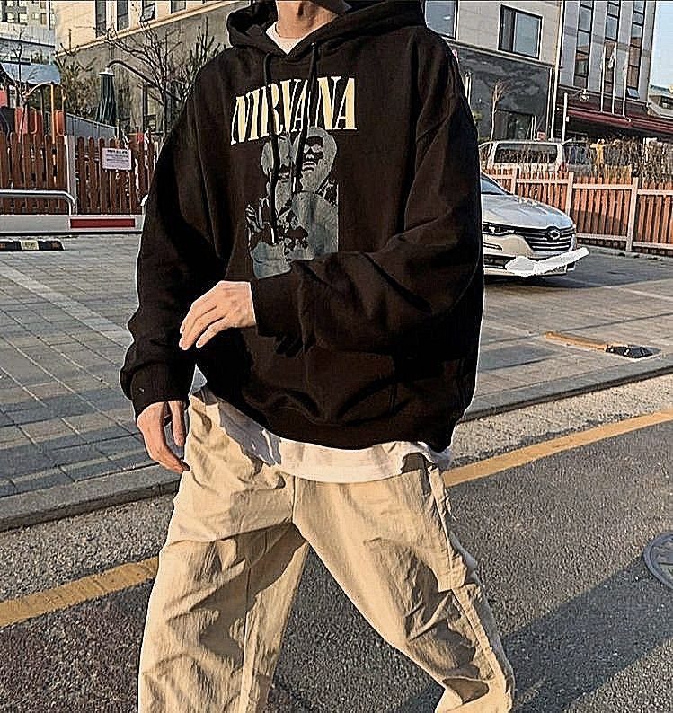 Person wearing a black Nirvana graphic hoodie and beige baggy cargo pants outdoors.