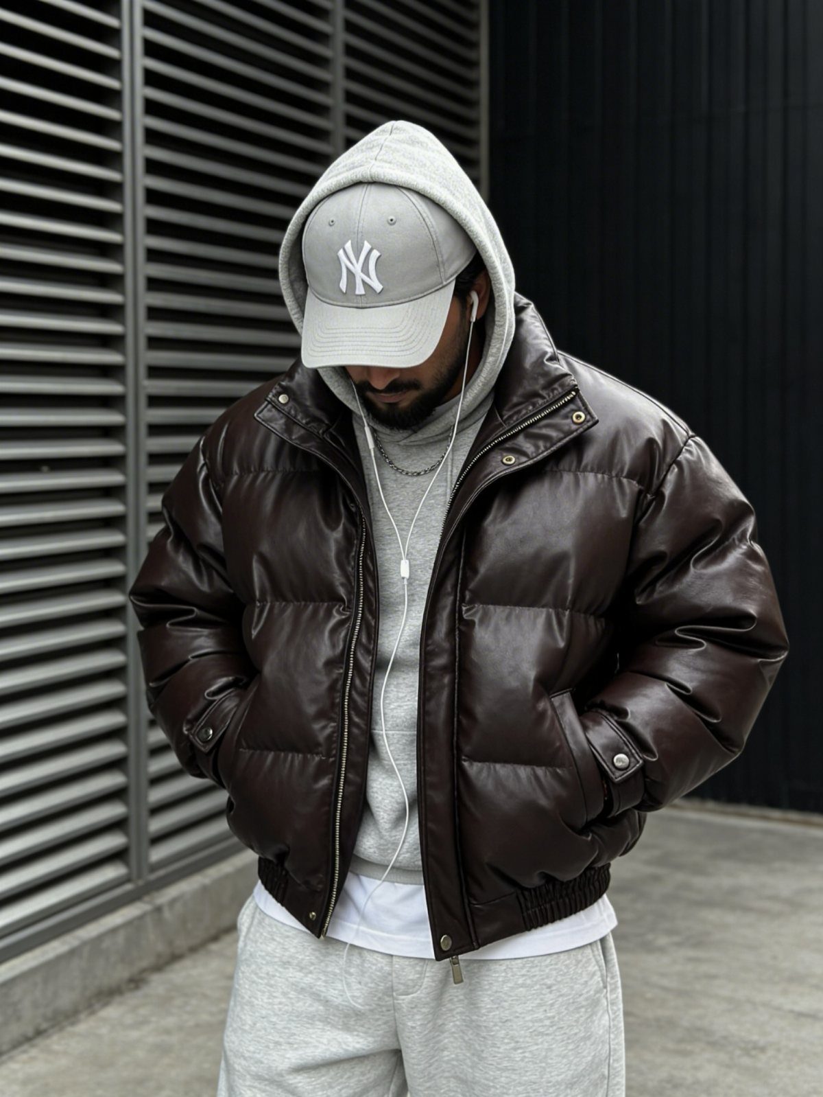 Man wearing a brown leather puffer jacket over a grey hoodie and sweatpants.