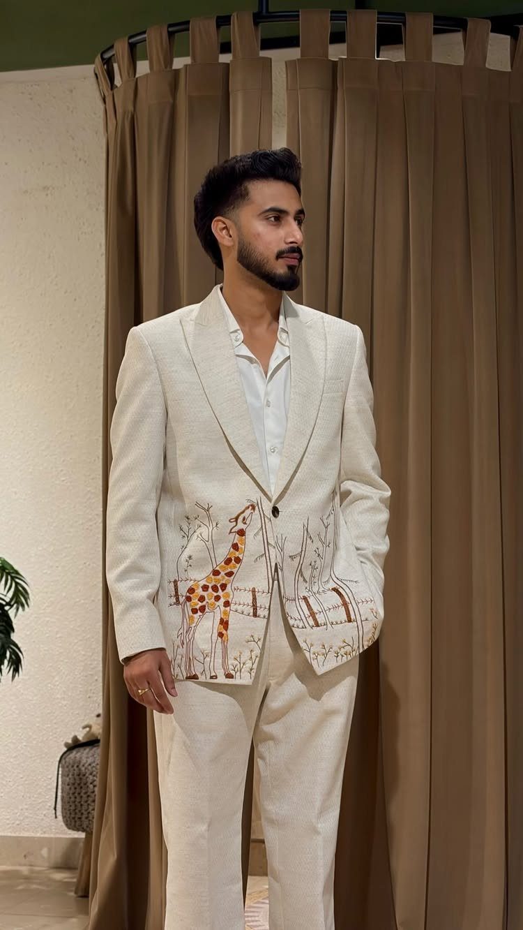 Man wearing a cream linen suit with a large giraffe print on the blazer.