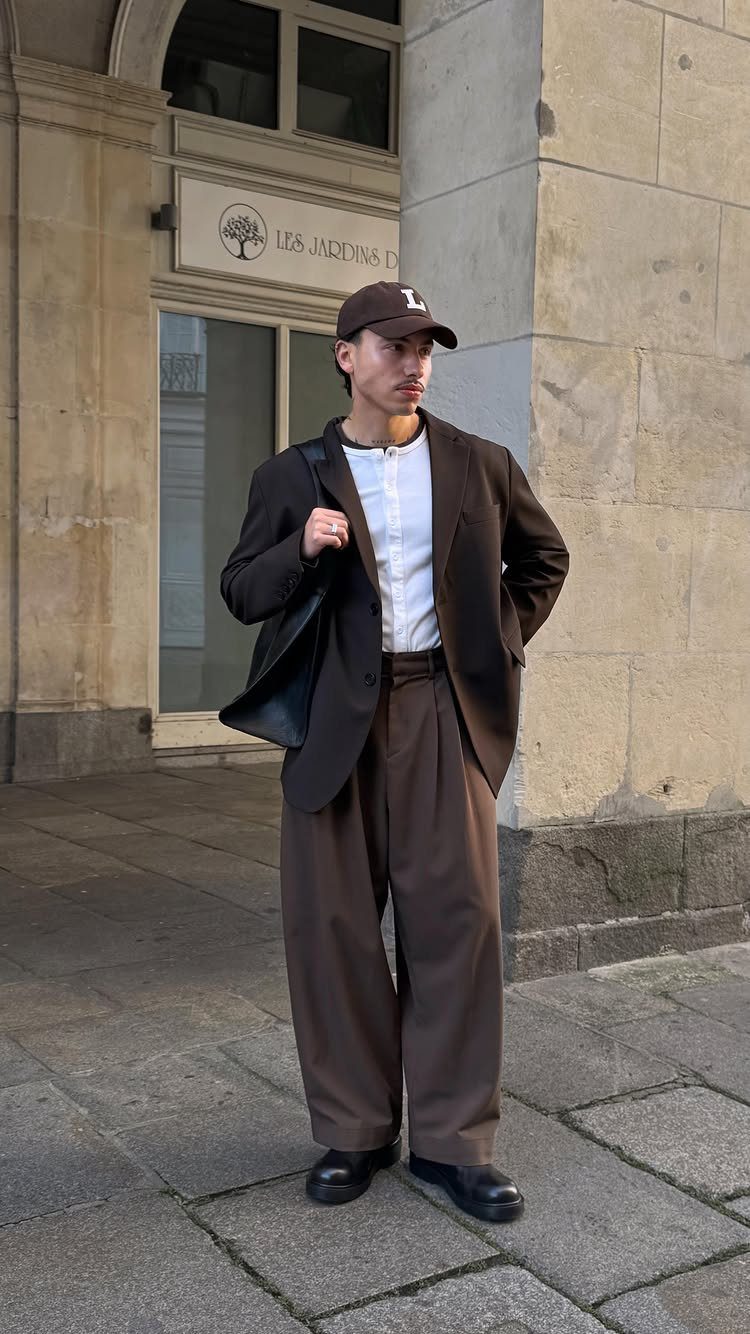 A man in brown trousers and a blazer standing on a city street.