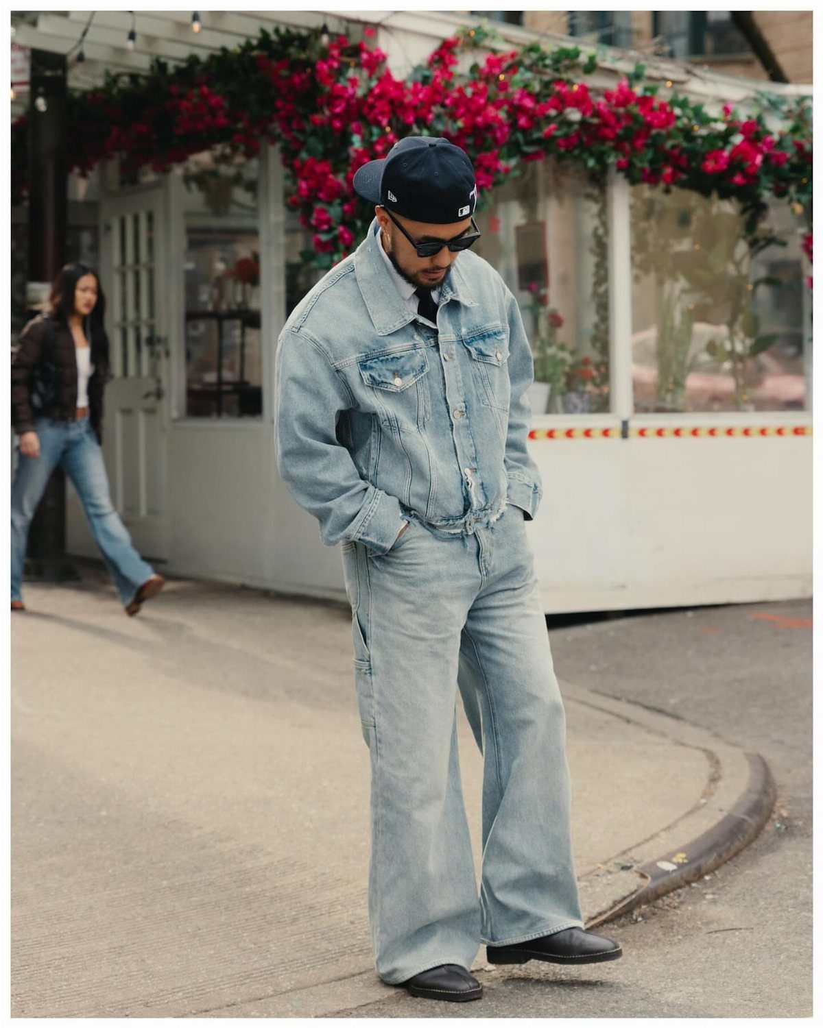 A man posing in a light wash denim jacket and wide-leg denim jeans outdoors.