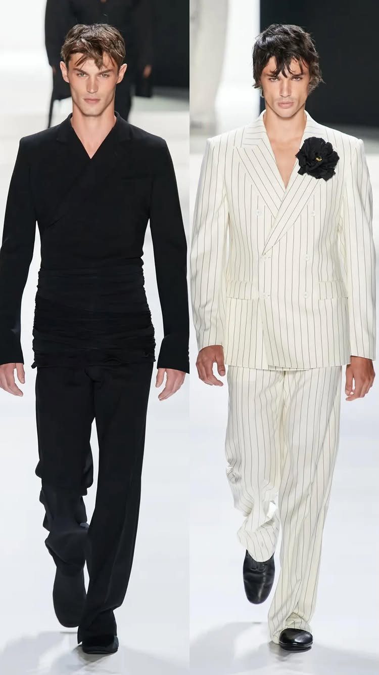 Two male models walking a runway wearing black and white designer suits.