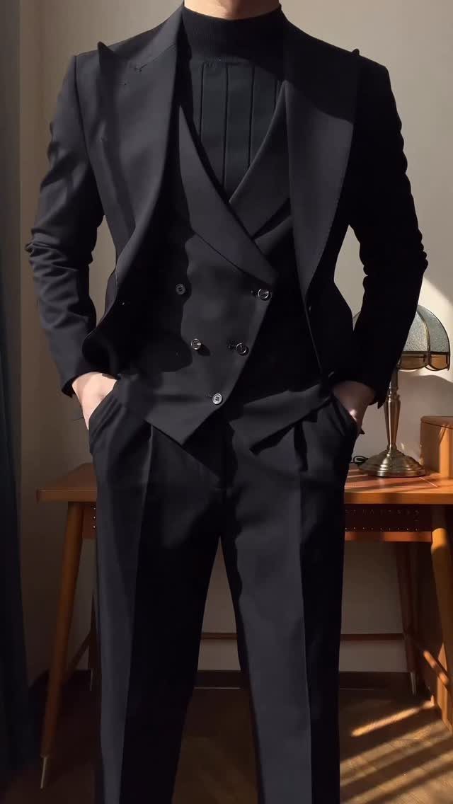 Man wearing a sharp, well-fitted black three-piece suit and a black turtleneck sweater.