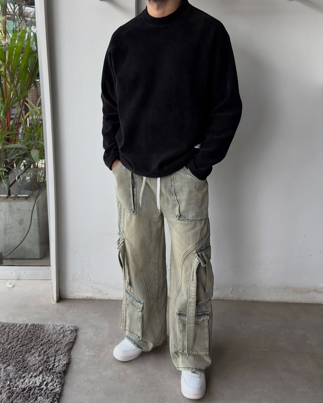 Person wearing a black ribbed sweater, light green cargo pants, and white sneakers.
