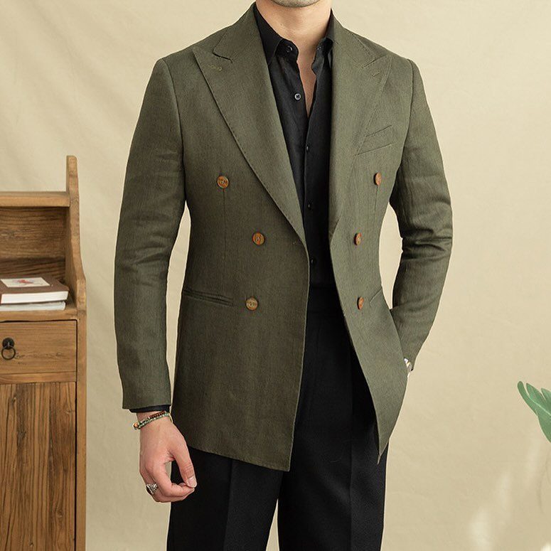 A man wearing an olive green double-breasted linen blazer and black shirt.