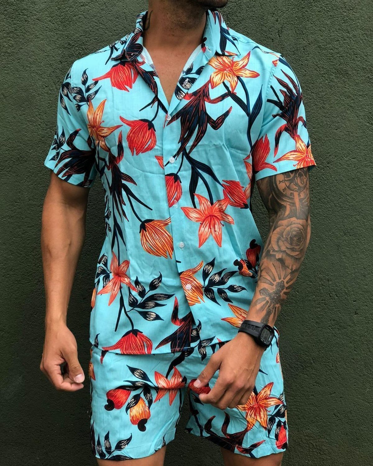 Man wearing a light blue matching shirt and shorts set with large orange floral patterns.