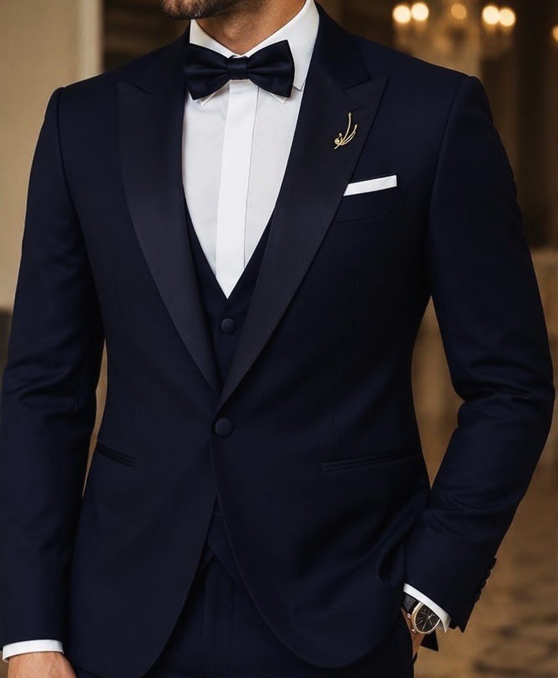 Man wearing a midnight blue three-piece tuxedo with a white shirt and navy bow tie.