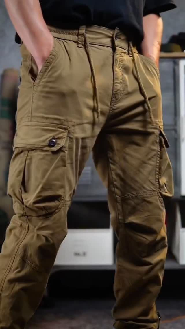A person wearing olive khaki cargo pants with large utility pockets and a black shirt.