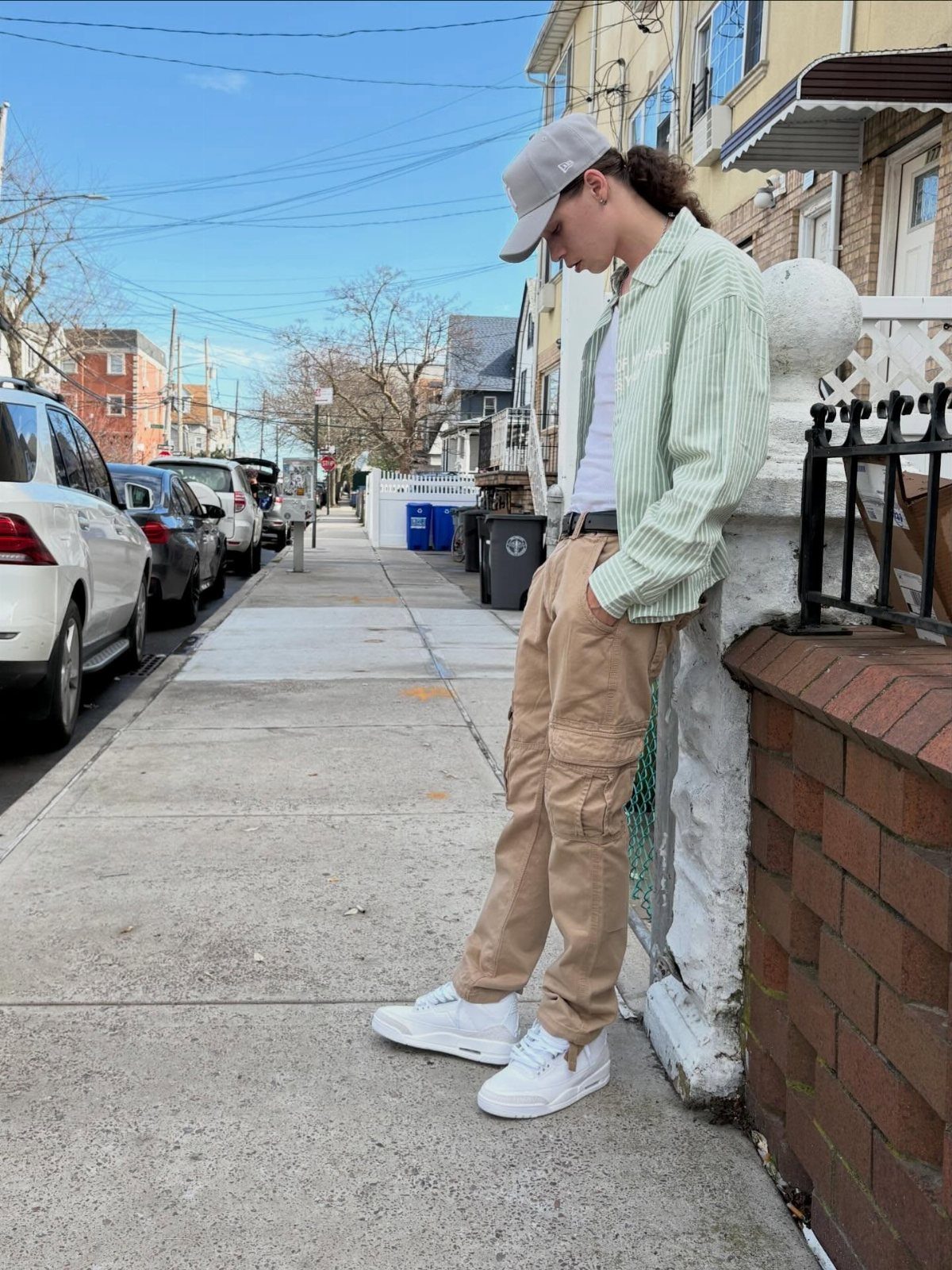 A person wearing khaki cargo pants and a striped button-down shirt standing on a sidewalk.