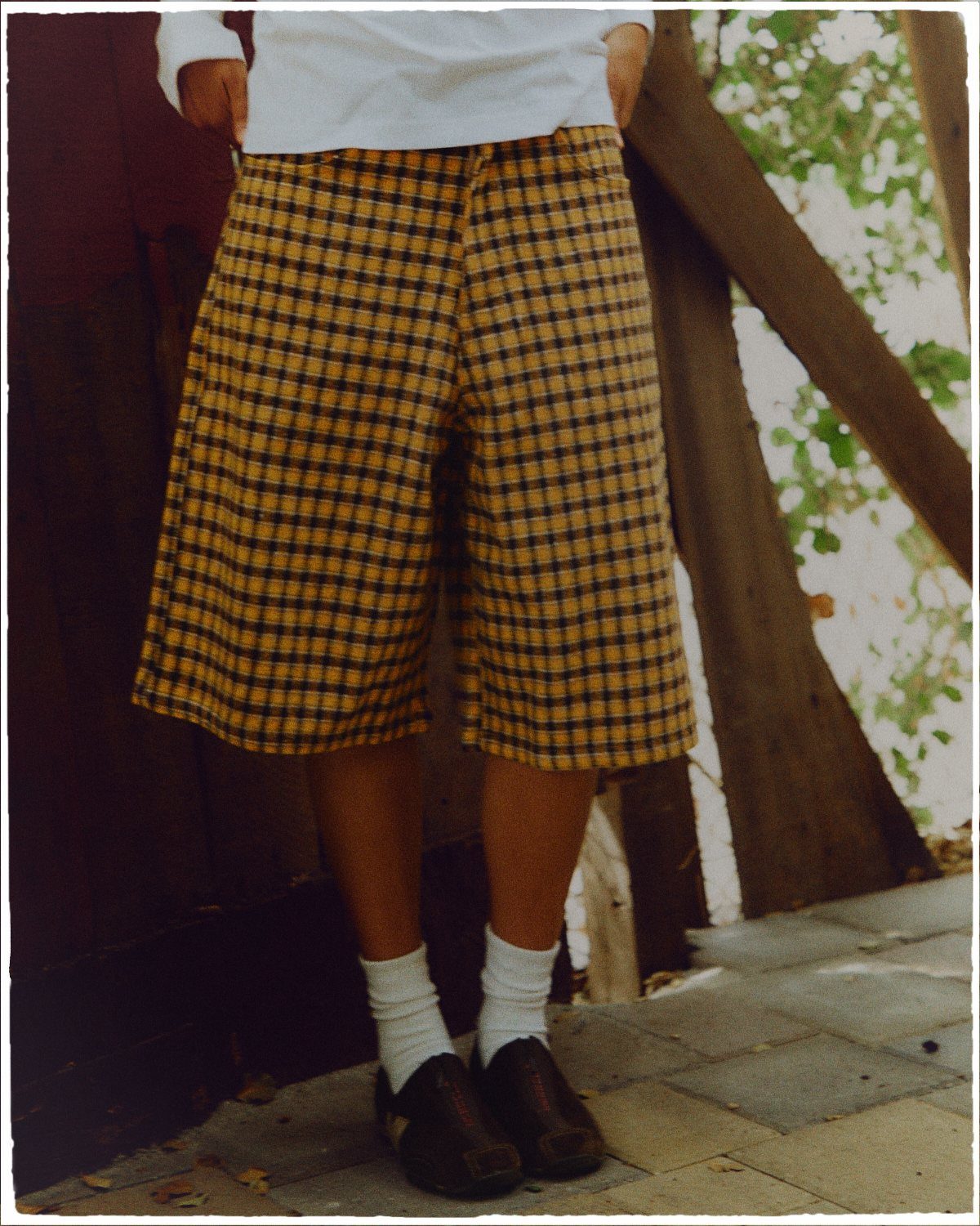 Person wearing yellow and black checkered wide-leg shorts with white socks and dark loafers.