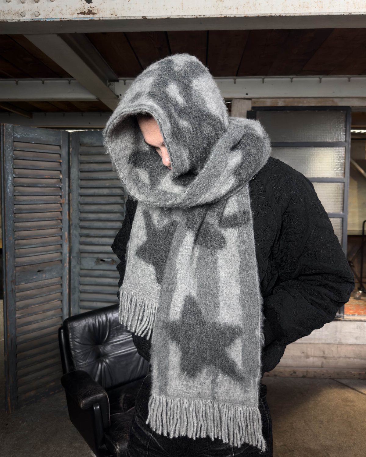 A person wearing a large grey star-patterned fuzzy scarf wrapped around their head.