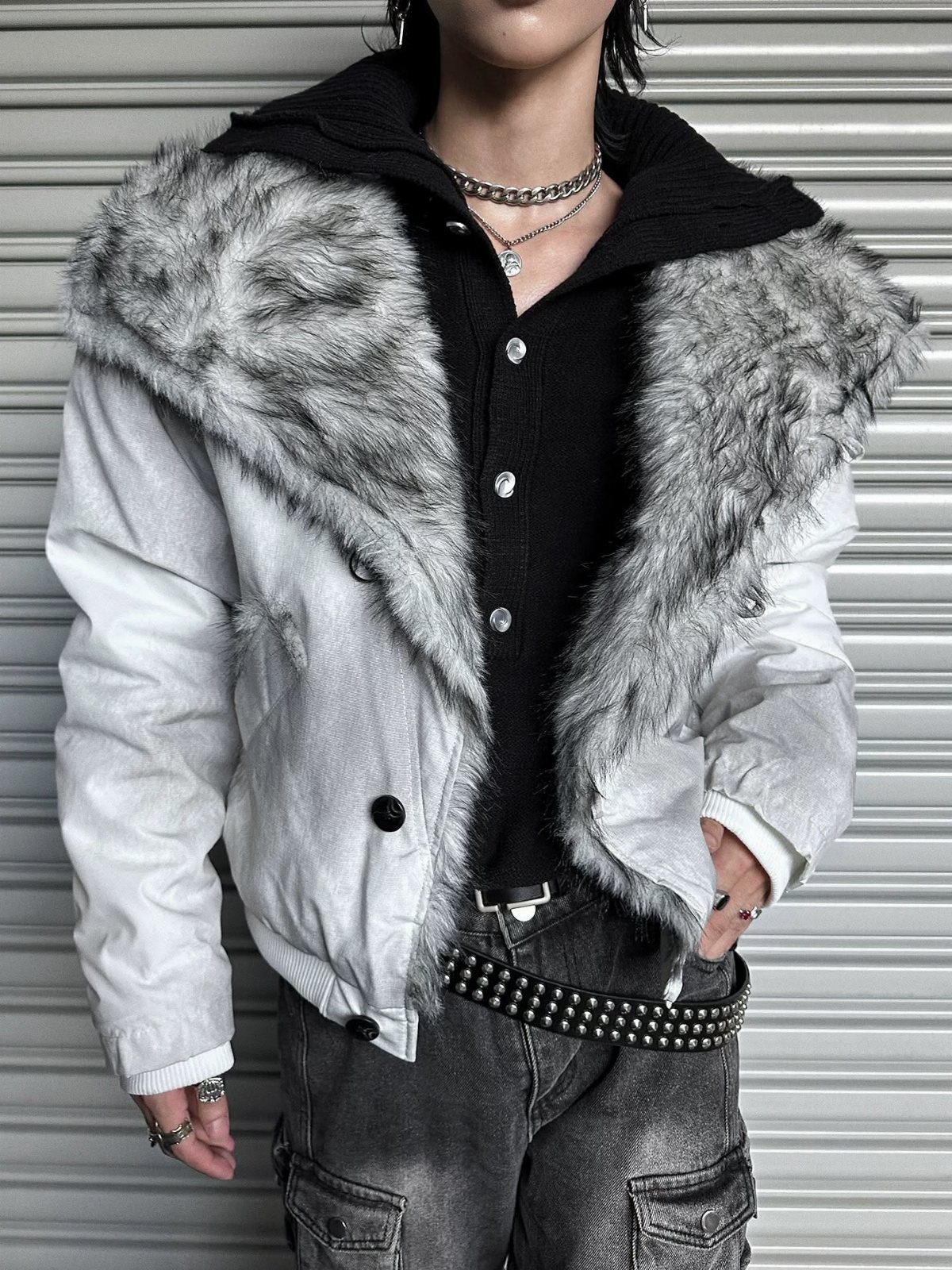 Person wearing a white jacket featuring a large grey faux fur collar and black shirt.