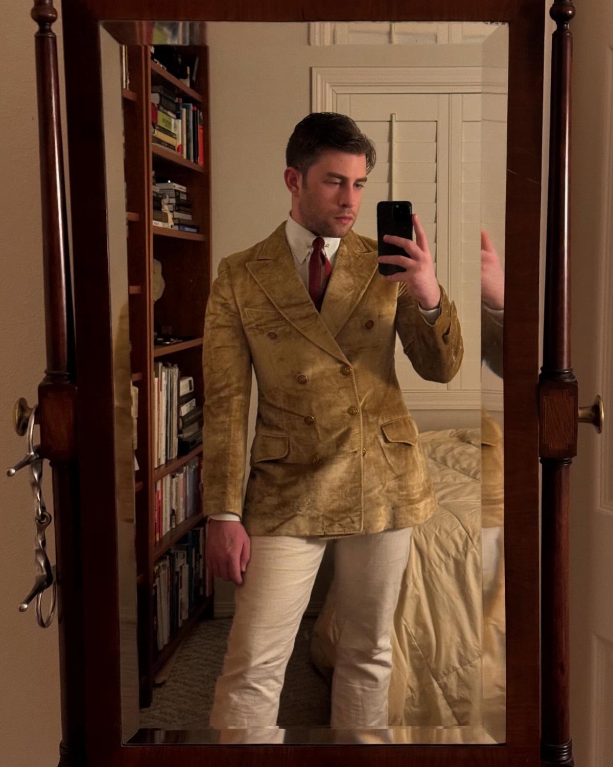 Man in a vintage tan double-breasted blazer and red tie taking a mirror selfie.