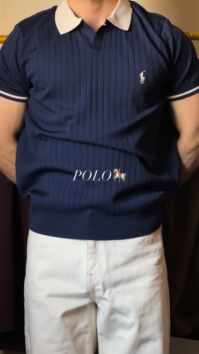 Man wearing a navy blue striped polo shirt with a white collar and white trousers.