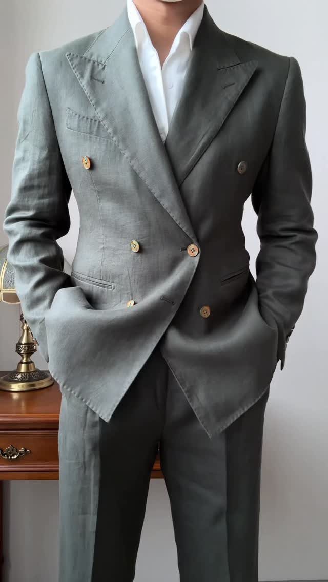 Man wearing a grey double-breasted linen suit with gold buttons and a white shirt.
