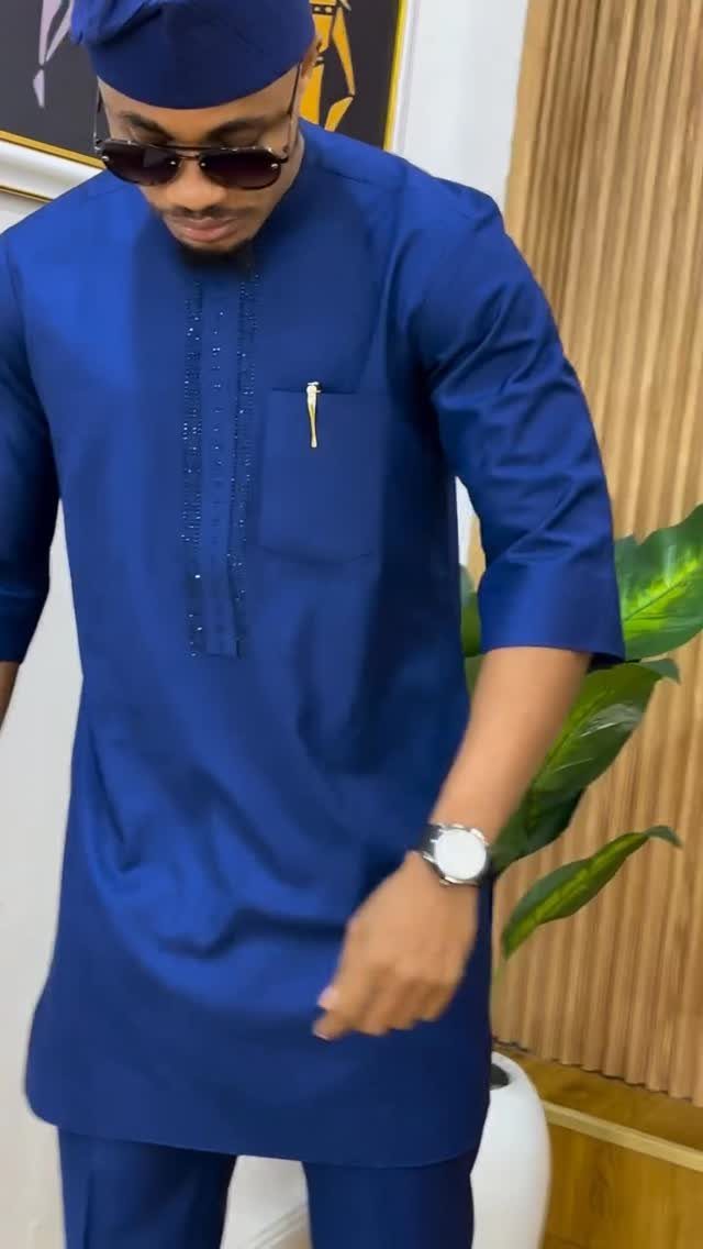 Man wearing a blue traditional African tunic, matching cap, and sunglasses.