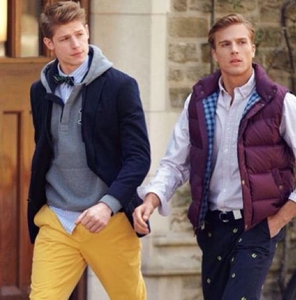 Two young men walking outdoors wearing layered casual preppy clothing and colorful trousers.