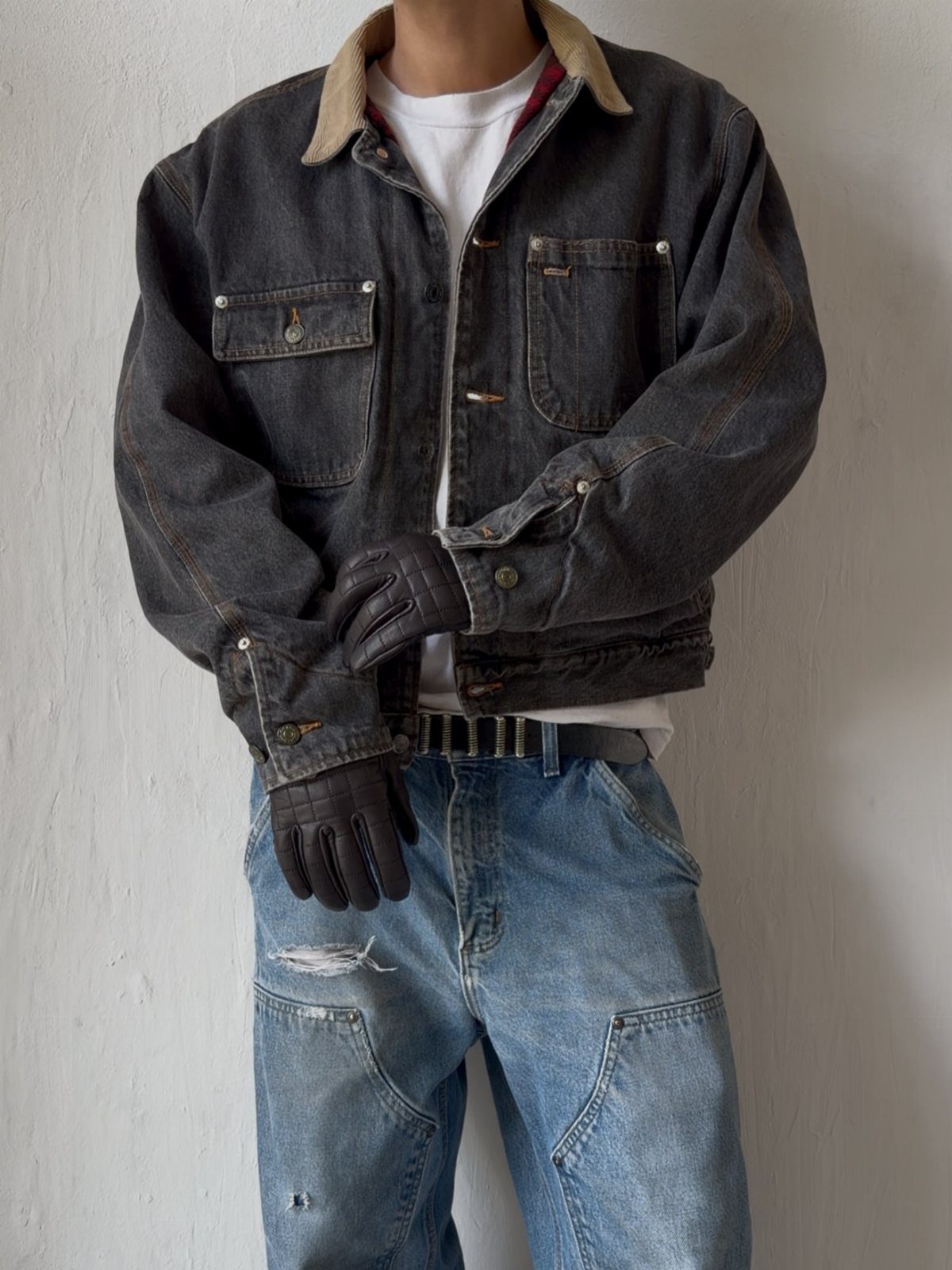 Person wearing a dark denim jacket, white t-shirt, and light blue distressed denim jeans.