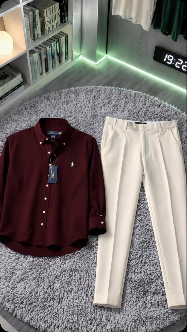 Maroon button-down shirt and cream pleated dress pants laid on a grey shaggy rug.