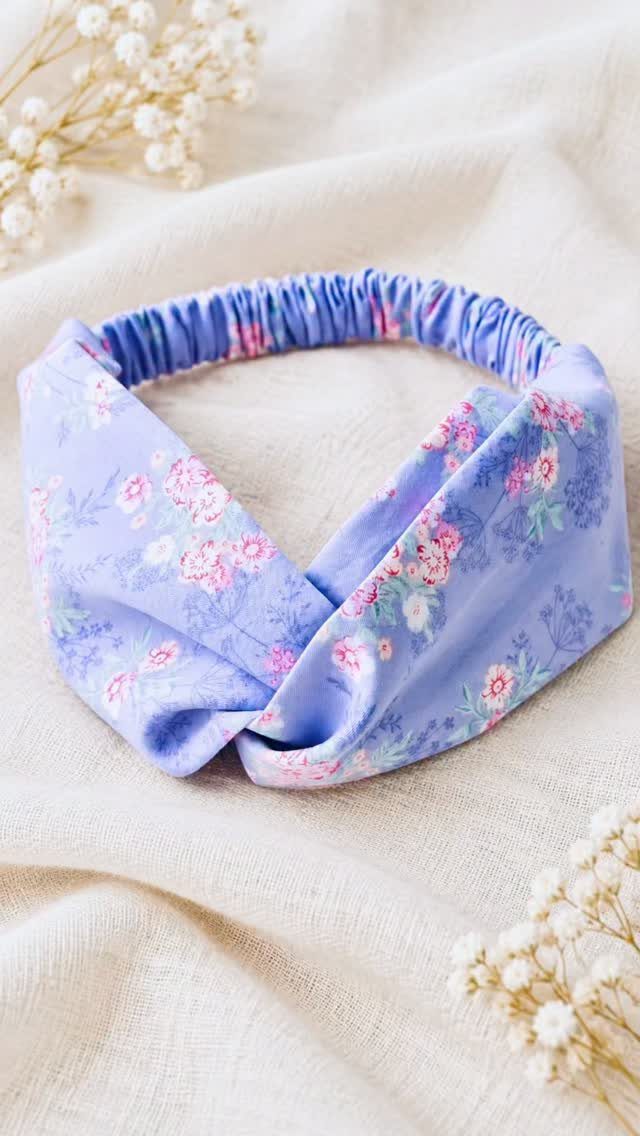 A lavender floral fabric headband with a twisted knot on cream fabric.