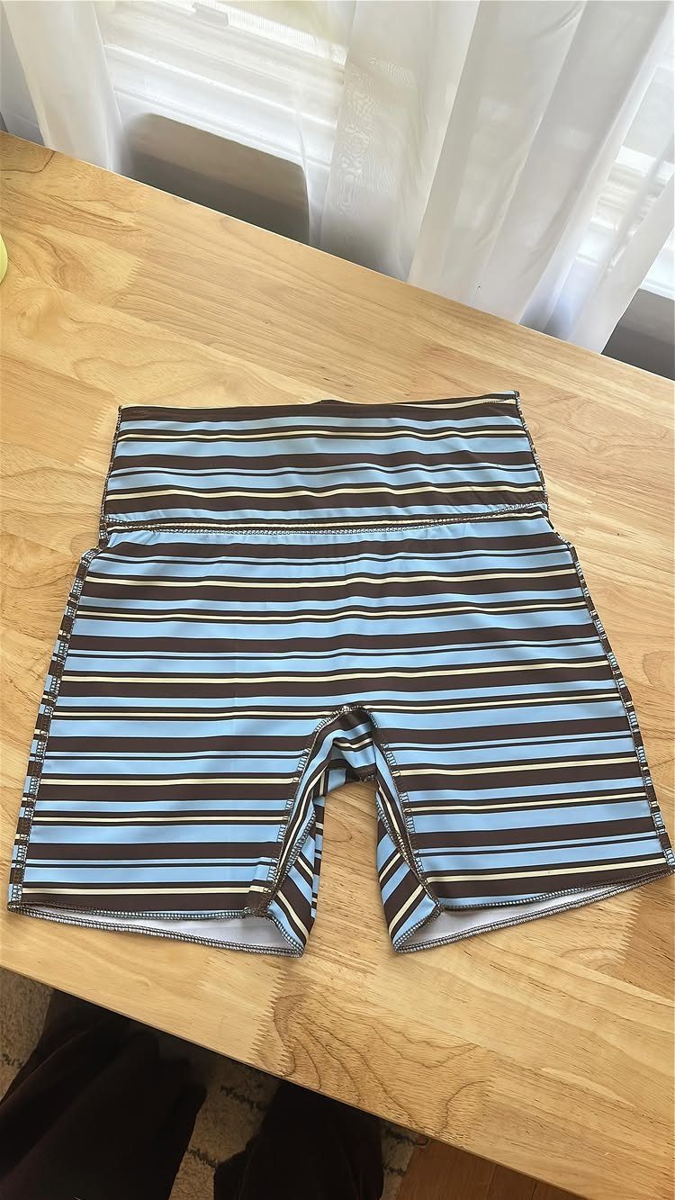 Striped high-waisted spandex shorts lying flat on a wooden table near a window.