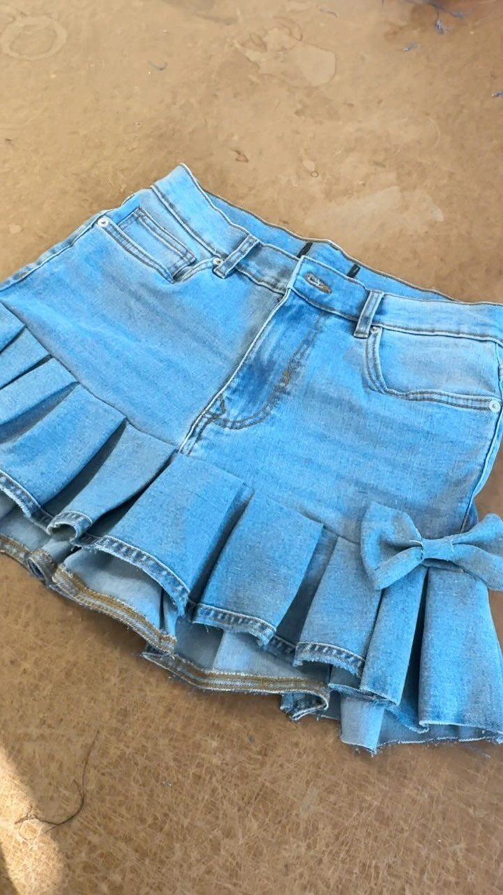 A light blue denim mini skirt featuring a ruffled tiered hem and a small bow.