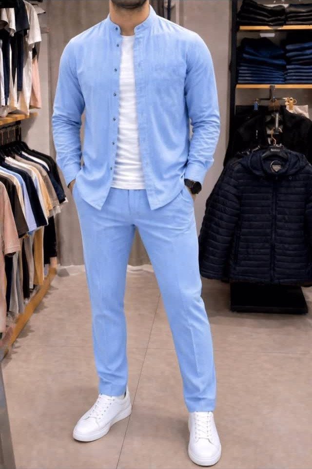 A man wearing a light blue shirt and matching trousers with white sneakers in a clothing store.