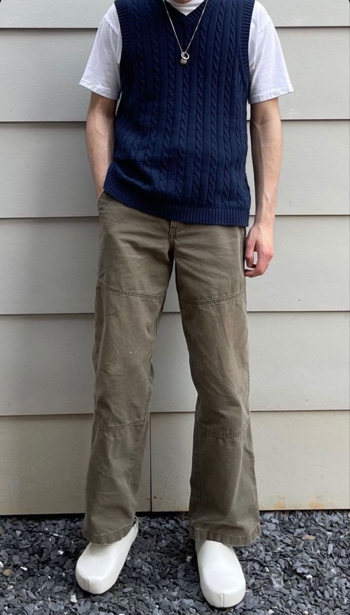 A person wearing a navy sweater vest, white t-shirt, olive pants, and white clogs.
