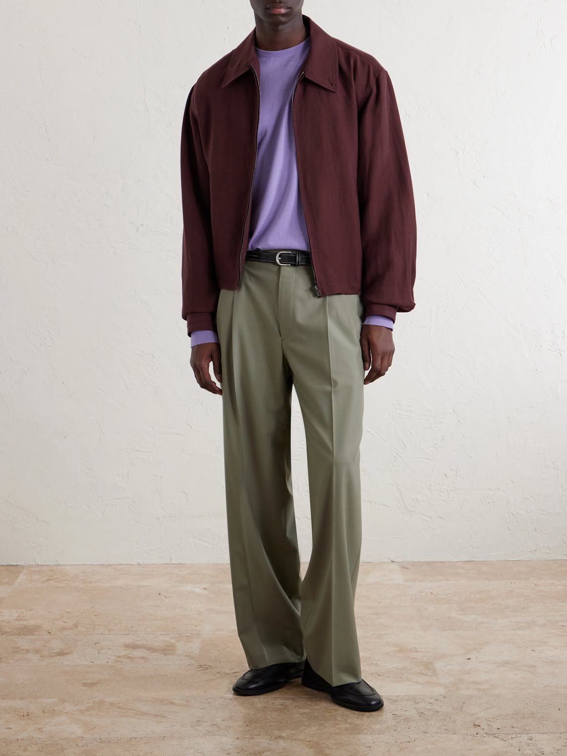 A person wearing a maroon jacket, lavender t-shirt, and olive green trousers.