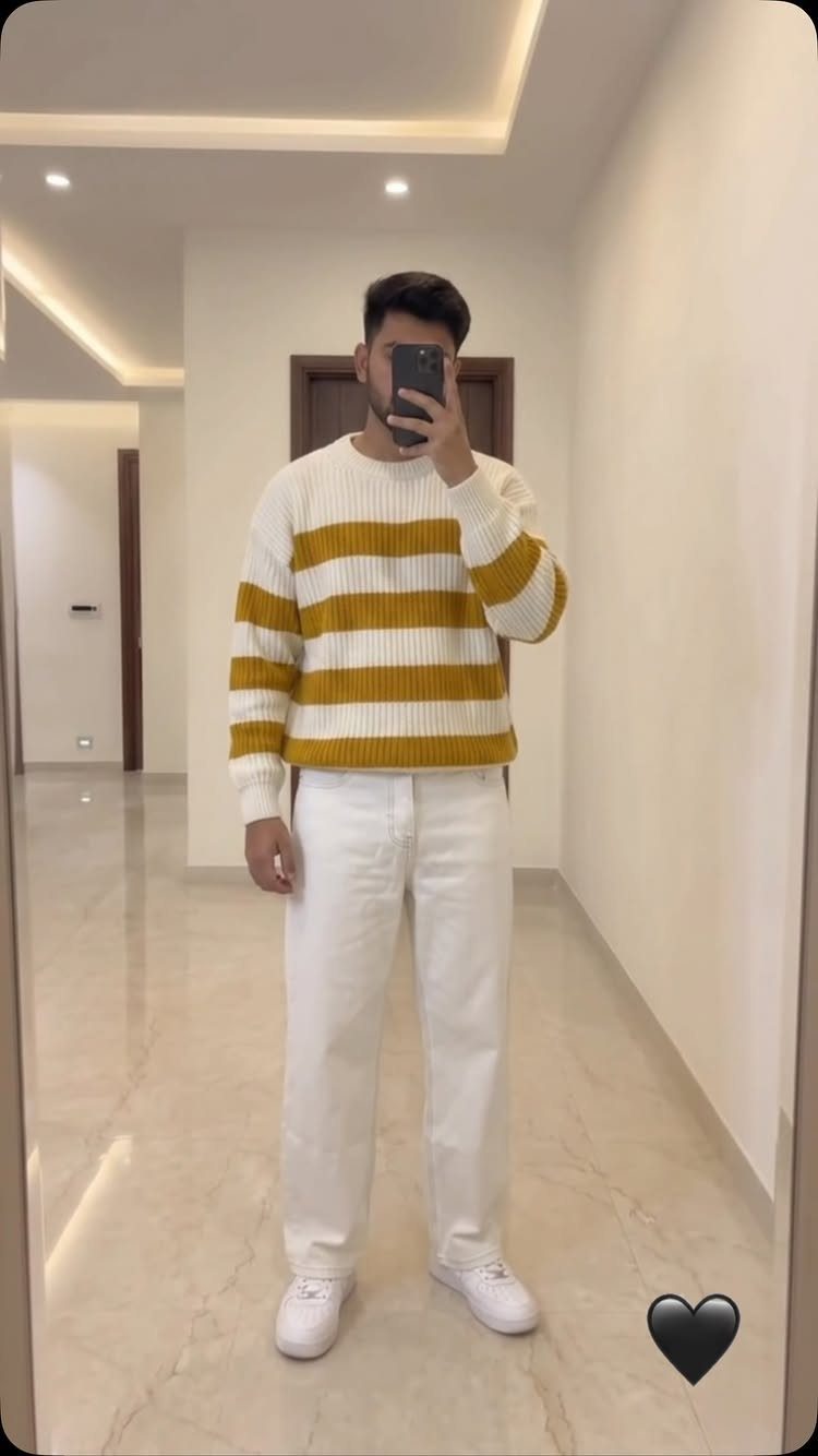 Man in a yellow and white striped chunky knit sweater and white pants.