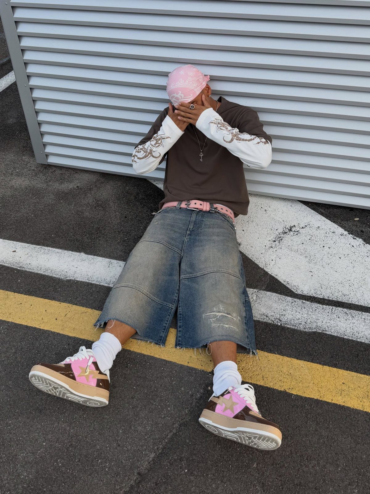 A person sitting on the ground wearing brown and pink statement sneakers with white socks.